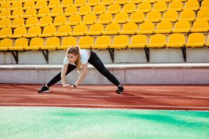 Portrait of a fitness woman doing warm up exercises at stadium
